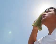 A man looks up and wipes his forehead with a towel